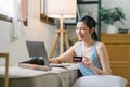 A happy young woman is shown shopping online using her laptop and credit card at home. Royalty Free Stock Photo