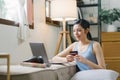 A happy young woman is shown shopping online using her laptop and credit card at home. Royalty Free Stock Photo