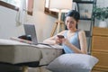 A happy young woman is shown shopping online using her laptop and credit card at home. Royalty Free Stock Photo