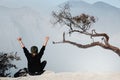 Girl sit on rock above volcano Kawah Ijen acid lake