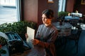 Happy young woman sits by the table in cafe Royalty Free Stock Photo