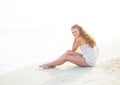 Happy young woman sitting on beach in the evening Royalty Free Stock Photo