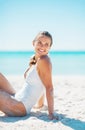 Happy young woman sitting on beach and looking on copy space Royalty Free Stock Photo