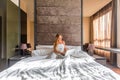 Happy young woman sitting in bed, using laptop in a modern home hotel bedroom Royalty Free Stock Photo