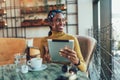 Young woman sitting in cafe holding digital tablet and credit card in hand, shopping online Royalty Free Stock Photo