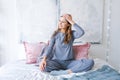 Happy young woman sitting in comfortable bed, arms outstretched after waking up Royalty Free Stock Photo