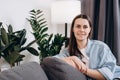 Happy young woman sitting on couch at home, smiling looking at camera. Portrait of adorable girl 20s old years relaxing on sofa. Royalty Free Stock Photo