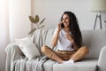 Happy young woman sitting on couch, talking on phone Royalty Free Stock Photo