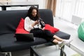 Happy young woman sitting on couch and using modern dslr photo camera Royalty Free Stock Photo