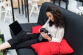 Happy young woman sitting on couch and using modern dslr photo camera Royalty Free Stock Photo