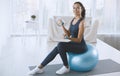 Lovely young woman sitting on fitness ball and exercising with dumbbells at home, empty space Royalty Free Stock Photo