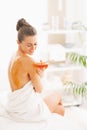 Happy young woman sitting on massage table with honey plate Royalty Free Stock Photo