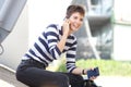 Happy young woman sitting outside with cellphone and passport Royalty Free Stock Photo