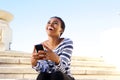 Happy young woman sitting outside using mobile phone Royalty Free Stock Photo