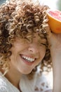 A happy young woman is sitting in a park and smiling, holding a grapefruit in her hand. Portrait of a Woman with Curly Royalty Free Stock Photo