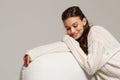 Happy young woman sitting on sofa at home and looking at camera. Portrait of comfortable woman in winter clothes relaxing on Royalty Free Stock Photo