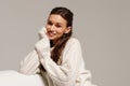 Happy young woman sitting on sofa at home and looking at camera. Portrait of comfortable woman in winter clothes relaxing on Royalty Free Stock Photo