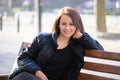 Happy young woman sitting on street bench enjoying free time during work break on warm autumn day. Wellness and resting Royalty Free Stock Photo