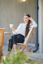 Young woman sitting on the terrace of the cafe in sunny day and drinking coffee Royalty Free Stock Photo