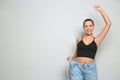 Happy young woman with slim body in oversized jeans on light background, space for text. Weight loss