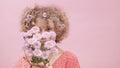 Happy young woman smelling bouquet of spring roses. Portrait of caucasian girl with flowers in her curly hair Royalty Free Stock Photo