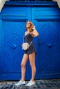 Happy young woman smiling against blue wooden door. Outdoor portrait of beautiful teen girl having fun Royalty Free Stock Photo