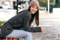 Happy young woman smiling broadly, wearing transparent eyeglasses,  gray sweater and pink hat. Outdoor image of pretty female Royalty Free Stock Photo