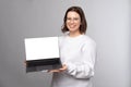 Happy young woman smiling and holding laptop with blank screen with copyspace Royalty Free Stock Photo