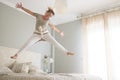 Happy young woman is smiling jumping on bed in the morning wake up - happy female people young adult have fun inthe bedroom with Royalty Free Stock Photo