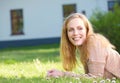 Happy young woman smiling and relaxing on grass outdoors Royalty Free Stock Photo