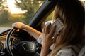 Happy young woman speaking by mobile phone while driving car. Business woman talking phone call in automobile. Unsafely