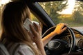 Happy young woman speaking by mobile phone while driving car. Business woman talking phone call in automobile. Unsafely