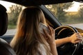 Happy young woman speaking by mobile phone while driving car. Business woman talking phone call in automobile. Unsafely