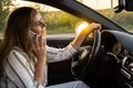 Happy young woman speaking by mobile phone while driving car. Business woman talking phone call in automobile. Unsafely