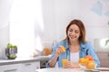 Happy young woman squeezing orange juice into glass