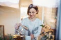 A young woman standing indoors in kitchen, pouring tea. Shot through glass. Royalty Free Stock Photo