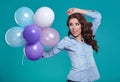 Happy young woman standing over blue wall and holding balloons. Royalty Free Stock Photo