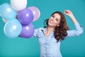 Happy young woman standing over blue wall and holding balloons. Royalty Free Stock Photo