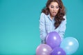 Happy young woman standing over blue wall and holding balloons. Royalty Free Stock Photo