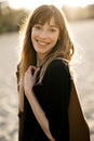 Happy young woman standing on sand on the beach at sunset. Royalty Free Stock Photo