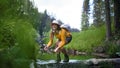 Happy young woman standing by stream on a walk outdoors in summer nature. Royalty Free Stock Photo