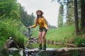 Happy young woman standing by stream on a walk outdoors in summer nature. Royalty Free Stock Photo