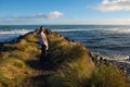 Happy young woman stands on coastline of natural seascape scenery in New Zealand