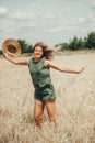 Happy young woman with straw hat in hands enjoying sun on cereal field Royalty Free Stock Photo