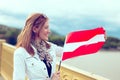 Happy young woman stretching Austrian flag on bridge