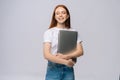 Happy young woman student holding laptop computer with closed eyes on isolated gray background. Royalty Free Stock Photo