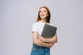 Happy young woman student holding laptop computer and looking away on  gray background. Royalty Free Stock Photo