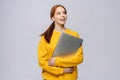 Happy young woman student holding laptop computer and looking away on isolated gray background. Royalty Free Stock Photo