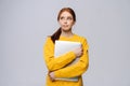 Happy young woman student holding laptop computer and looking away on isolated gray background. Royalty Free Stock Photo