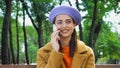 happy young woman in stylish autumn clothes talking on smartphone in park.